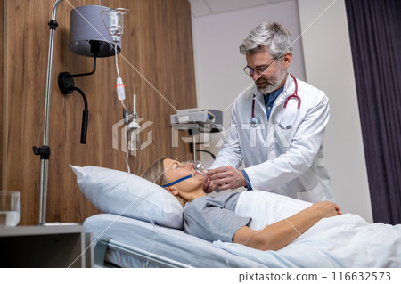 Doctor fixing oxygen mask on a female patient face in clinic 116632573