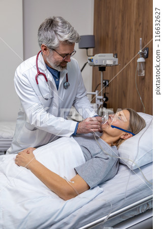 Doctor working in an intensive therapy department and putting oxygen mask on a patient 116632627