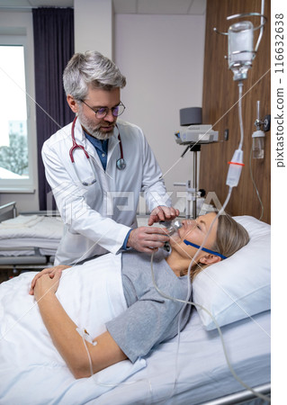 Doctor putting an oxygen mask on a female patient Doctor putting an oxygen mask on a female patient 116632638