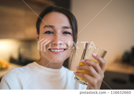 Pretty young woman with a glass of orange juice in hands Pretty young woman with a glass of orange juice in hands 116632660
