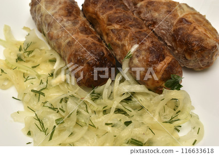 Bovarian sausages with onions on a plate. A delicious meat snack. 116633618