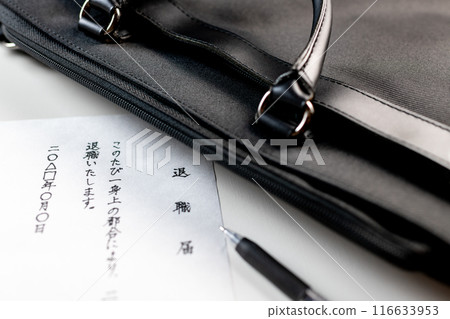A handwritten resignation letter, a black gel ink pen and part of a black business bag placed on a white table A handwritten resignation letter, a black gel ink pen and part of a black business bag placed on a white table 116633953