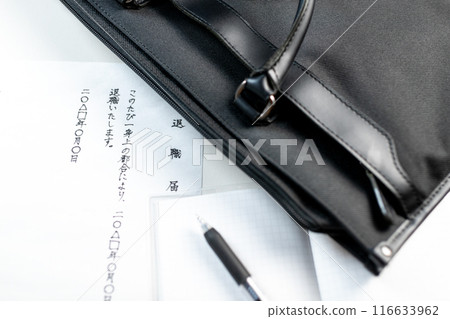 A handwritten resignation letter and a black gel ink pen on a notepad placed next to a business bag 116633962
