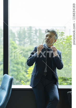 Gray-haired businessman by the window Gray-haired businessman by the window 116634169