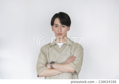 一名20歲出頭的年輕人，抱著雙臂，看著鏡頭。 116634188