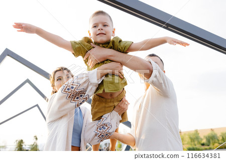 On a Beautiful Sunny Day, Parents Enjoy Lifting Their Child up in the Air, Creating Joyful Memories That Will Last a Lifetime 116634381