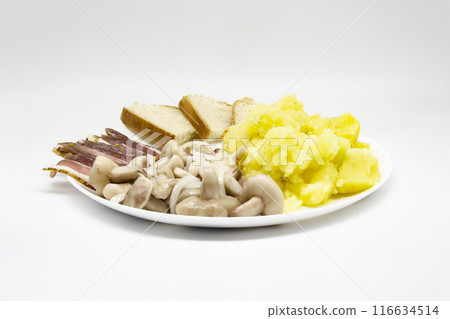 Pickled butter mushrooms with onions on a plate with bacon, potatoes and slices of bread isolated on a white background. Delicious Ukrainian meal for lunch or dinner. 116634514