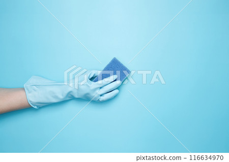 Womans hand in rubber glove holds yellow dishwashing sponge. House cleaning. Copy space Womans hand in rubber glove holds yellow dishwashing sponge. House cleaning. Copy space 116634970