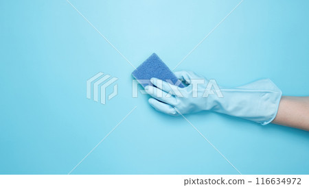 Womans hand in rubber glove holds yellow dishwashing sponge. House cleaning. Copy space Womans hand in rubber glove holds yellow dishwashing sponge. House cleaning. Copy space 116634972