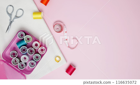 Composition with various threads and sewing accessories on pink background. Top view, copy space Composition with various threads and sewing accessories on pink background. Top view, copy space 116635072