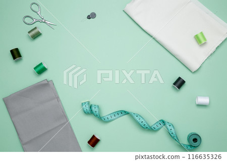 Composition with various threads and sewing accessories on green background. Top view, copy space 116635326