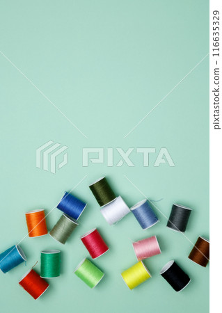Multicolored sewing threads on green background. Top view, copy space Multicolored sewing threads on green background. Top view, copy space 116635329