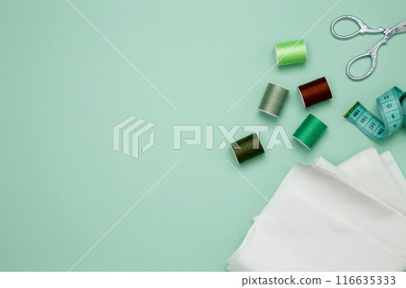 Composition with various threads and sewing accessories on green background. Top view, copy space Composition with various threads and sewing accessories on green background. Top view, copy space 116635333