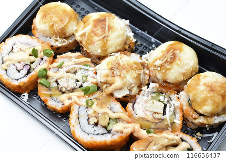 Fish rolls on a black backing.  Rice snack. 116636437