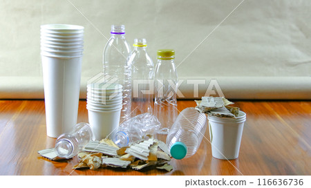 White paper coffee cup, used paper, and cardboard box on a brown surface, awaiting recycling. White paper coffee cup, used paper, and cardboard box on a brown surface, awaiting recycling. 116636736
