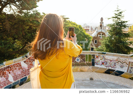 Redhead Woman with tote bag taking picture of Barcelona from Guell Park. Concept of travel, tourism, technology and vacation in city. Rear view Redhead Woman with tote bag taking picture of Barcelona from Guell Park. Concept of travel, tourism, technology and vacation in city. Rear view 116636982