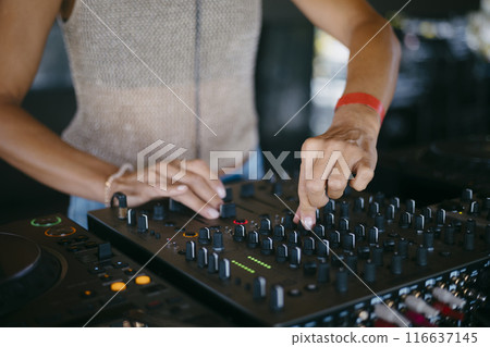 woman DJ Hands creating and regulating music on dj console mixer in a music festival 116637145