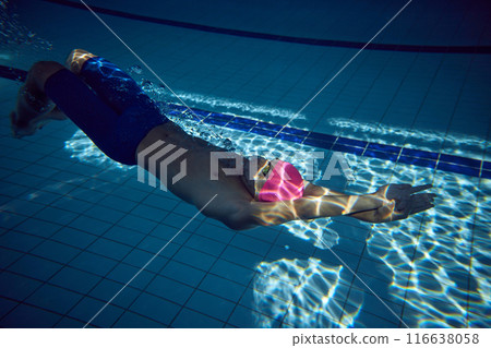 Intensity of competition. Man diving forward with perfect form, his athletic physique and pink cap visible amidst water bubbles. Intensity of competition. Man diving forward with perfect form, his athletic physique and pink cap visible amidst water bubbles. 116638058