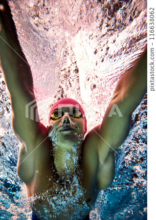 Swimmer's intense training session. Man with tones physique and precise strokes, swimming under water in motion with focused expression. Swimmer's intense training session. Man with tones physique and precise strokes, swimming under water in motion with focused expression. 116638062