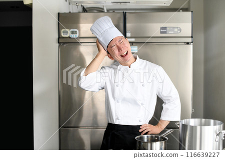 Worried young Asian female cook holding a pot Worried young Asian female cook holding a pot 116639227