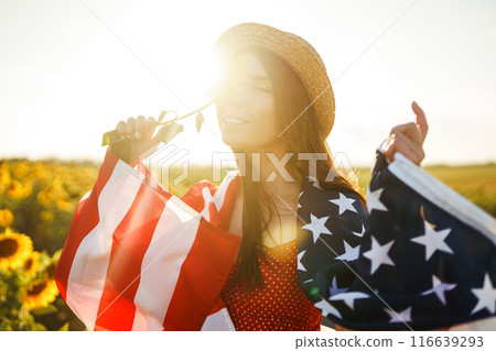 Beautiful girl in hat with the American flag in a sunflower field. 4th of July. Fourth of July. Freedom Beautiful girl in hat with the American flag in a sunflower field. 4th of July. Fourth of July. Freedom 116639293