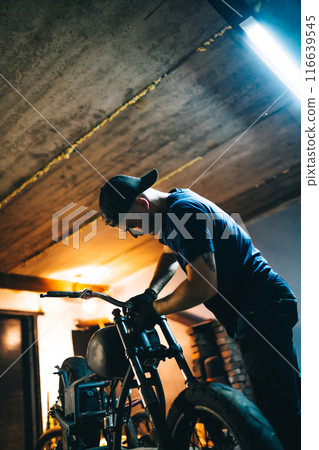 Motorcycle repair. Young man repairing motorbike in garage. Mechanic fixing motorcycle engine. Motorcycle repair. Young man repairing motorbike in garage. Mechanic fixing motorcycle engine. 116639545