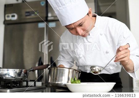 Young asian male chef serving food on plates in the kitchen Young asian male chef serving food on plates in the kitchen 116639813