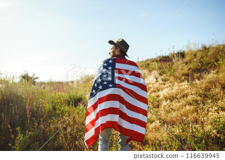 4th of July. American Flag.Patriotic holiday. Traveler with the flag of America. Beautiful sunset light. American style. 116639945