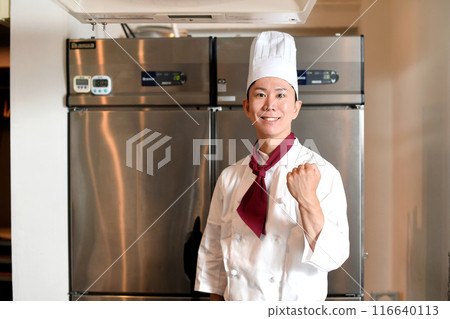 A young male chef doing a fist pump in the kitchen 116640113