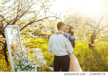Beautiful loving couple in blooming gardens. Wedding concept. Great sunset light. Lovely newlyweds. 116640174