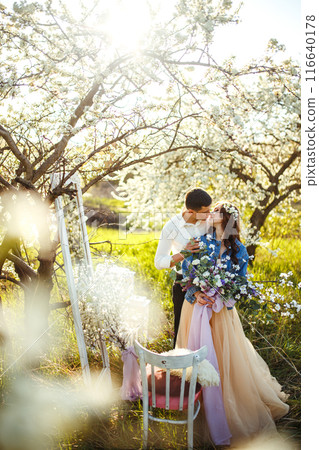 Beautiful loving couple in blooming gardens. Wedding concept. Great sunset light. Lovely newlyweds. 116640178
