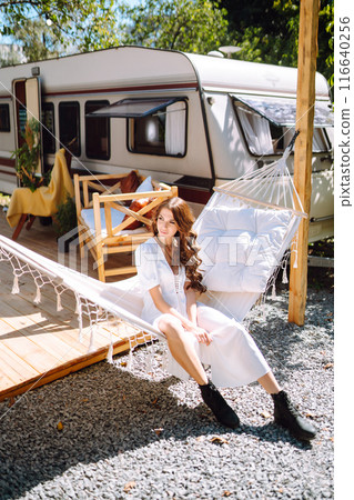 Beautiful stylish bride near trailer. Camping season. Marriage. Happy newlywed woman. 116640256