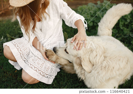Owner and labrador retriever dog in a yard. Woman in a white dress. Golden retriever. 116640421