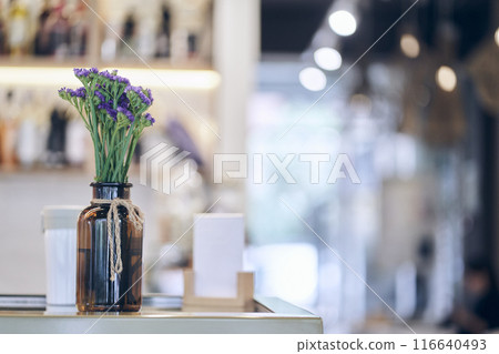Focus on the vase with dried flowers on the table. The unfocused interior of the restaurant. There is a place to copy. An image of a coffee shop with a side to use as a background. High quality photo 116640493