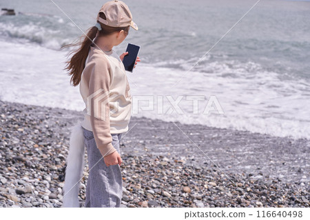 An unrecognizable child with a smartphone. A quadrobra girl takes a selfie on the seashore. The concept of entertainment where children dress up as animals. High quality photo An unrecognizable child with a smartphone. A quadrobra girl takes a selfie on the seashore. The concept of entertainment where children dress up as animals. High quality photo 116640498