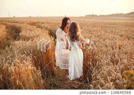 Family in a summer field. Sensual photo. Cute little girl. Woman in a white dress. 116640569