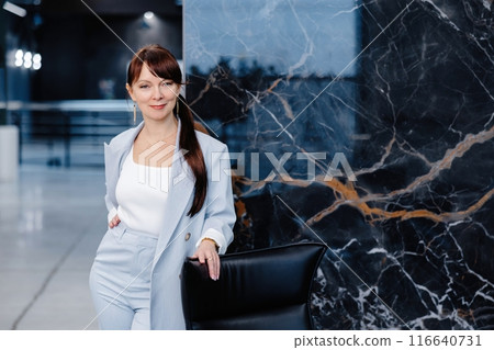 Woman in blue suit standing in front of marble wall 116640731