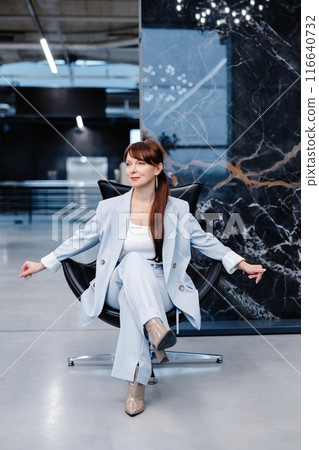Woman in light blue suit posing in a modern office space Woman in light blue suit posing in a modern office space 116640732