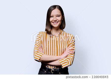Young confident smiling woman with crossed arms on white background 116640843