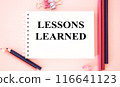LESSONS LEARNED text on pink background and with pencils.The image shows a slogan Lessons Learnd written on a pink notebook. Bright picture. Concept Image. Can be used as template, signboard, banner 116641123