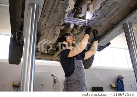Auto mechanic working under car in service garage Auto mechanic working under car in service garage 116642530