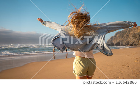 Carefree woman with arms out running on sandy Carefree woman with arms out running on sandy 116642866