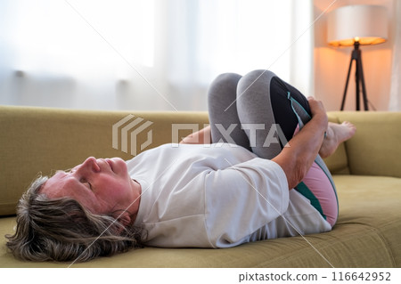 Senior caucasian woman doing doing yoga at home on sofa Senior caucasian woman doing doing yoga at home on sofa 116642952