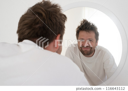 Tired mature caucasian man is looking at the mirror. Tired mature caucasian man is looking at the mirror. 116643112