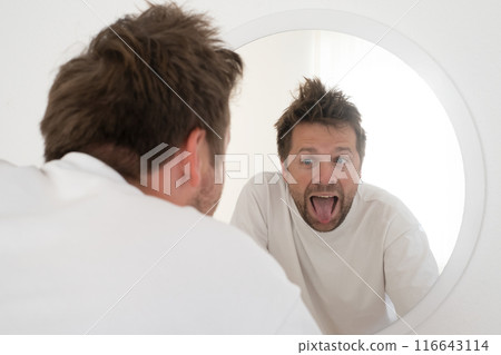 Tired mature caucasian man is looking at the mirror. Tired mature caucasian man is looking at the mirror. 116643114