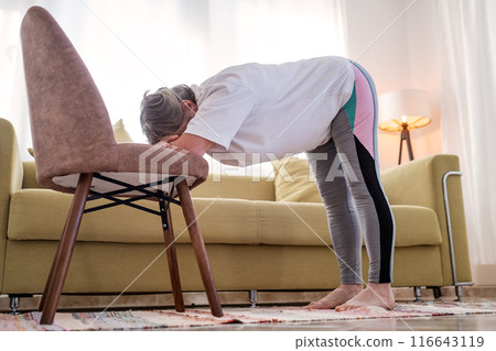 Senior caucasian woman doing yoga at home on chair Senior caucasian woman doing yoga at home on chair 116643119