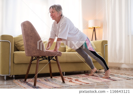 Senior caucasian woman doing yoga at home on chair Senior caucasian woman doing yoga at home on chair 116643121