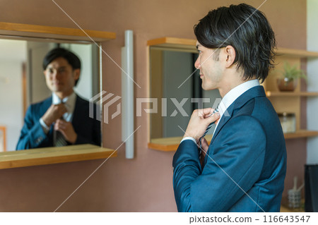 A young male businessman in a suit getting ready in the bathroom 116643547