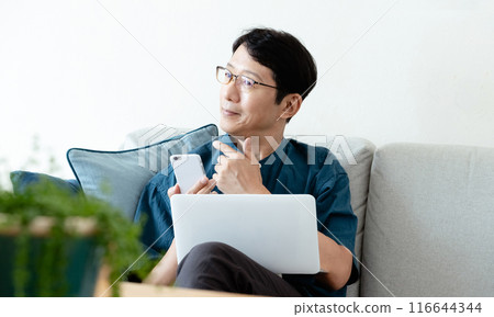 中年男子在沙發上操作電腦和智慧型手機 116644344