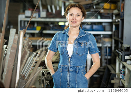 Woman employee of carpentry workshop took time out from work, stands resting Woman employee of carpentry workshop took time out from work, stands resting 116644605
